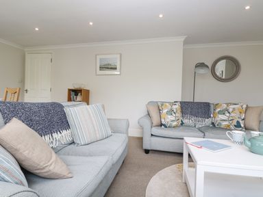 A living room with two sofas a white coffee table a floor lamp and a small bookshelf at Godrevy in Porthcurno
