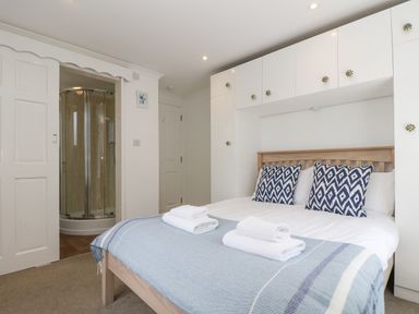 A bedroom with a double bed towels on the bed and a shower cubicle visible through an open door at Godrevy in Porthcurno