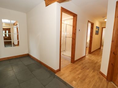 A hallway with slate and wood flooring a bathroom with a shower and three doorways at Y Tylwyth in Blaenau Ffestiniog