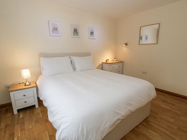 A bedroom with a double bed with white bedding two bedside tables with lamps and a wall mirror at Y Tylwyth in Blaenau Ffestiniog