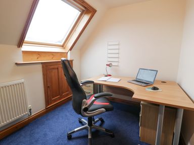 A small office with a desk chair laptop notebook and desk lamp under a skylight window at Y Tylwyth in Blaenau Ffestiniog