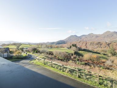 A rural landscape with a road fence and hills in the background at Y Tylwyth in Blaenau Ffestiniog