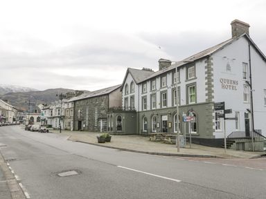 A street with parked cars and the Queens Hotel building on the right side at Y Tylwyth in Blaenau Ffestiniog