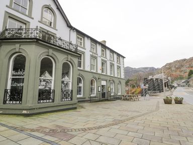 Exterior of the Queens Hotel with paved area and mountains in the background at Y Tylwyth in Blaenau Ffestiniog