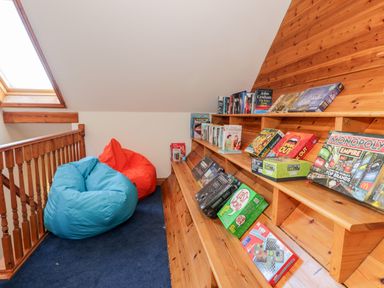 A loft area with blue and orange bean bags and shelves with board games and books at Y Tylwyth in Blaenau Ffestiniog