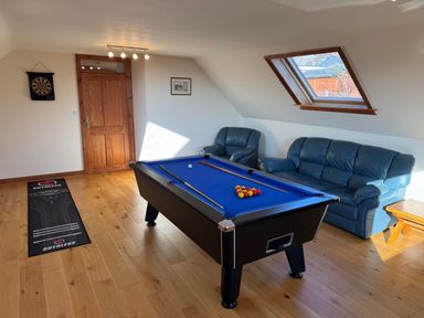 A game room with a pool table a dartboard blue leather sofas and a wooden floor at Y Tylwyth in Blaenau Ffestiniog