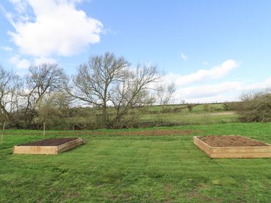 A garden area with two raised planting beds and trees in the background at Otters View in South Luffenham near Edith Weston