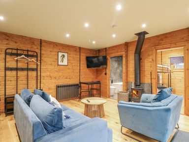 A living room with a sofa, armchair, and television at Otter's View South Luffenham near Edith Weston