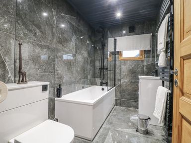 A bathroom with a bath tub, toilet, and sink at Otter's View in South Luffenham near Edith Weston