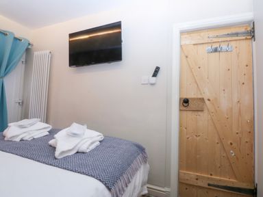 A bedroom with a bed and a television at Pine Cottage in Dinas Dinlle