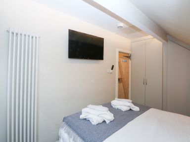 A bedroom with a television and towels on the bed at Pine Cottage Dinas Dinlle