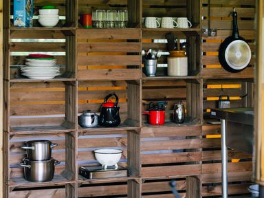 Wooden kitchen shelves with dishes glasses cookware and utensils near a metal sink at Oak Stockland near Dalwood