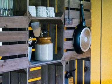 Wooden kitchen shelves with mugs, utensils in a jar, frying pan hanging on the side at Oak Stockland near Dalwood