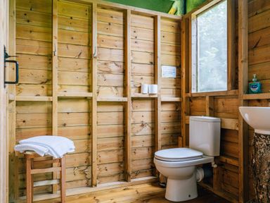A wooden bathroom with a toilet stool with towels a window and a sink at Oak in Stockland near Dalwood