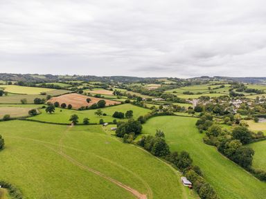 Aerial view of agricultural fields with scattered trees and a small village at Oak Stockland near Dalwood
