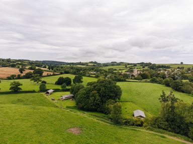 A rural landscape with green fields trees and farm buildings at Beech in Dalwood