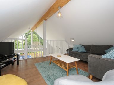 A living room with gray sofas blue cushions white coffee table and television at Otters Leap in Bideford