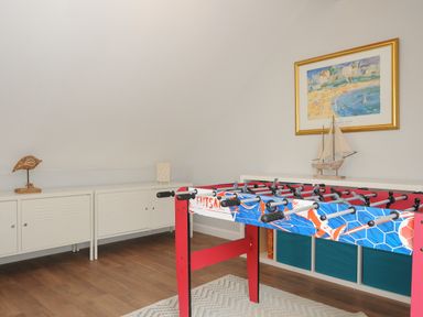 A room with a foosball table, white cabinets, and a framed painting with a model ship at Otters Leap in Bideford