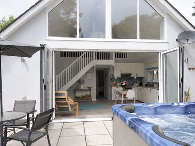 An open plan kitchen and living area with a wooden chair table and chairs outside by a hot tub at Otters Leap in Bideford