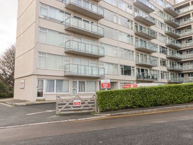 A multi-story apartment building with balconies and a gated parking area at 54 Croft Court in Tenby
