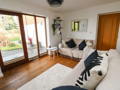A living room with two sofas pillows wooden floor glass door and small tables at Little Rondeval in Totnes
