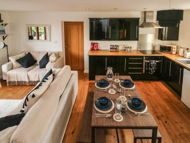 An open-plan kitchen and living area with a dining table set for four at Little Rondeval in Totnes