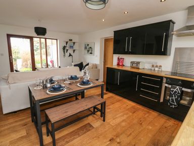 A kitchen and dining area with a wooden table set with blue dishes a beige sofa and black kitchen cabinets at Little Rondeval in Totnes