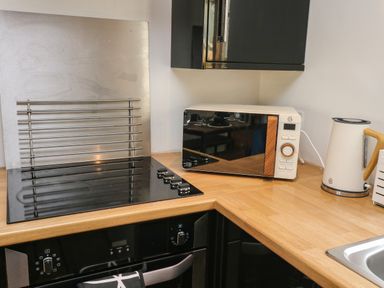 A kitchen corner with a stovetop oven microwave kettle and wooden countertop at Little Rondeval in Totnes