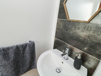 A bathroom sink with a tap and soap dispenser next to a towel on a towel rack at Little Rondeval in Totnes