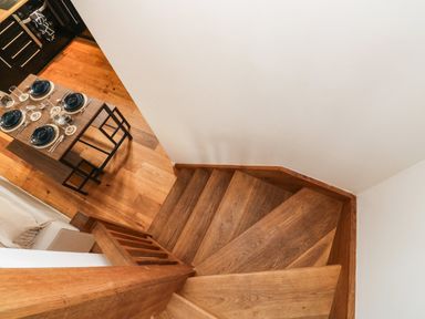 A wooden staircase leading down to a dining area with a set table at Little Rondeval in Totnes