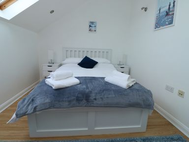 A bedroom with a double bed white linens blue blanket and towels on the bed at Little Rondeval in Totnes
