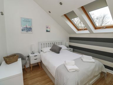 A bedroom with a double bed towels on bed slanted windows and bedside tables at Little Rondeval in Totnes