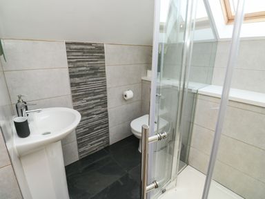 A bathroom with a sink a toilet a glass shower enclosure and a skylight at Little Rondeval in Totnes