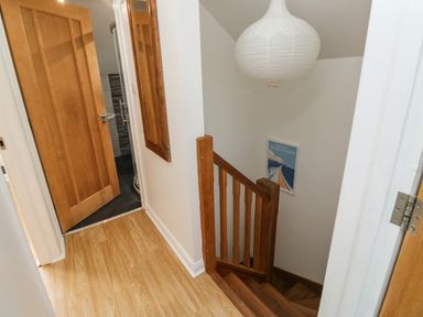 A staircase with wooden railing and a door leading to a bathroom with tiled walls at Little Rondeval in Totnes