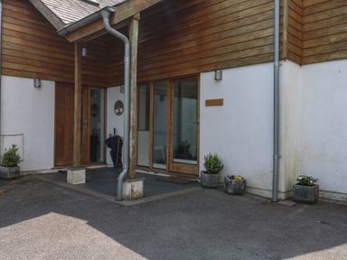 An exterior view of a building entrance with wooden doors glass panels a covered porch and potted plants at Little Rondeval in Totnes
