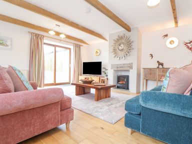 A living room with a wooden coffee table a fireplace two sofas and a television at Riviere Barton in Hayle