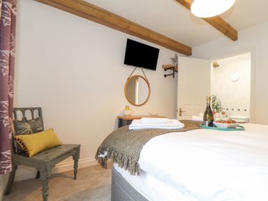 A bedroom with a bed a chair towels a mirror and a television at Riviere Barton in Hayle