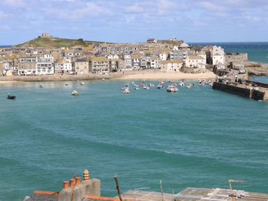 A coastal town with boats in the harbor and buildings along the shoreline at Riviere Barton in Hayle