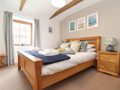 A bedroom with a wooden bed and bedside tables with lamps at Riviere Barton in Hayle