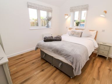 A bedroom with a bed with white and grey bedding and bedside tables at Puffins Rest in Goldsithney