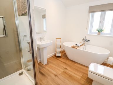 A bathroom with a shower cubicle sink bathtub toilet and window at Puffins Rest in Goldsithney
