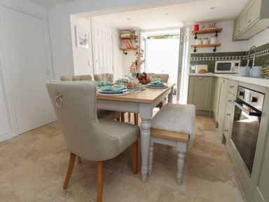 A kitchen with a dining table set with plates glasses and napkins at Belvedere Cottage in Weymouth