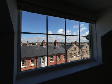 A view of rooftops and chimneys through a large window at Belvedere Cottage in Weymouth