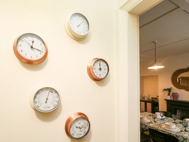 A wall with five round ClimeMET instruments near a doorway showing a dining room with a table set with dishes and glassware at Josie in Pentewan