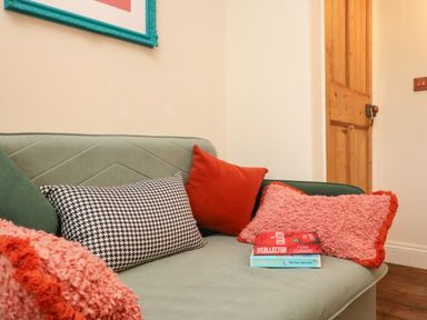 A couch with patterned and textured cushions and two books on it near a wooden door at Josie in Pentewan