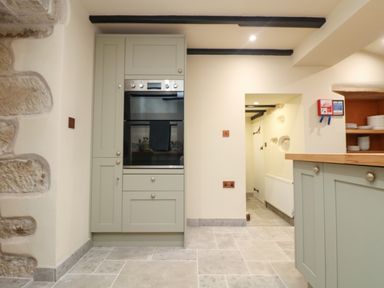 A kitchen with built-in oven cabinets stone floor and open doorway at Josie in Pentewan