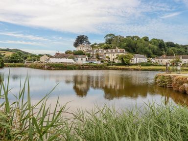 A body of water with houses and trees in the background at Josie in Pentewan