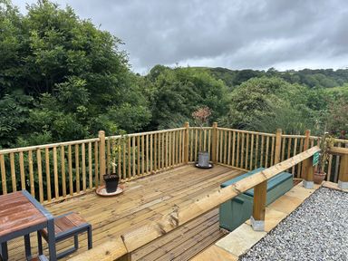 An outdoor deck area with a table, chairs, and plants at Josie in Pentewan