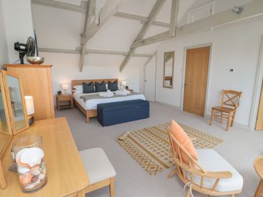 A bedroom with a bed blue bench wooden furniture and a patterned rug at Eider Cottage in Warkworth