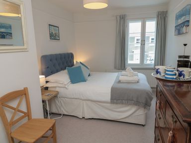 A bedroom with a bed with blue cushions and folded towels on the bed at Eider Cottage in Warkworth